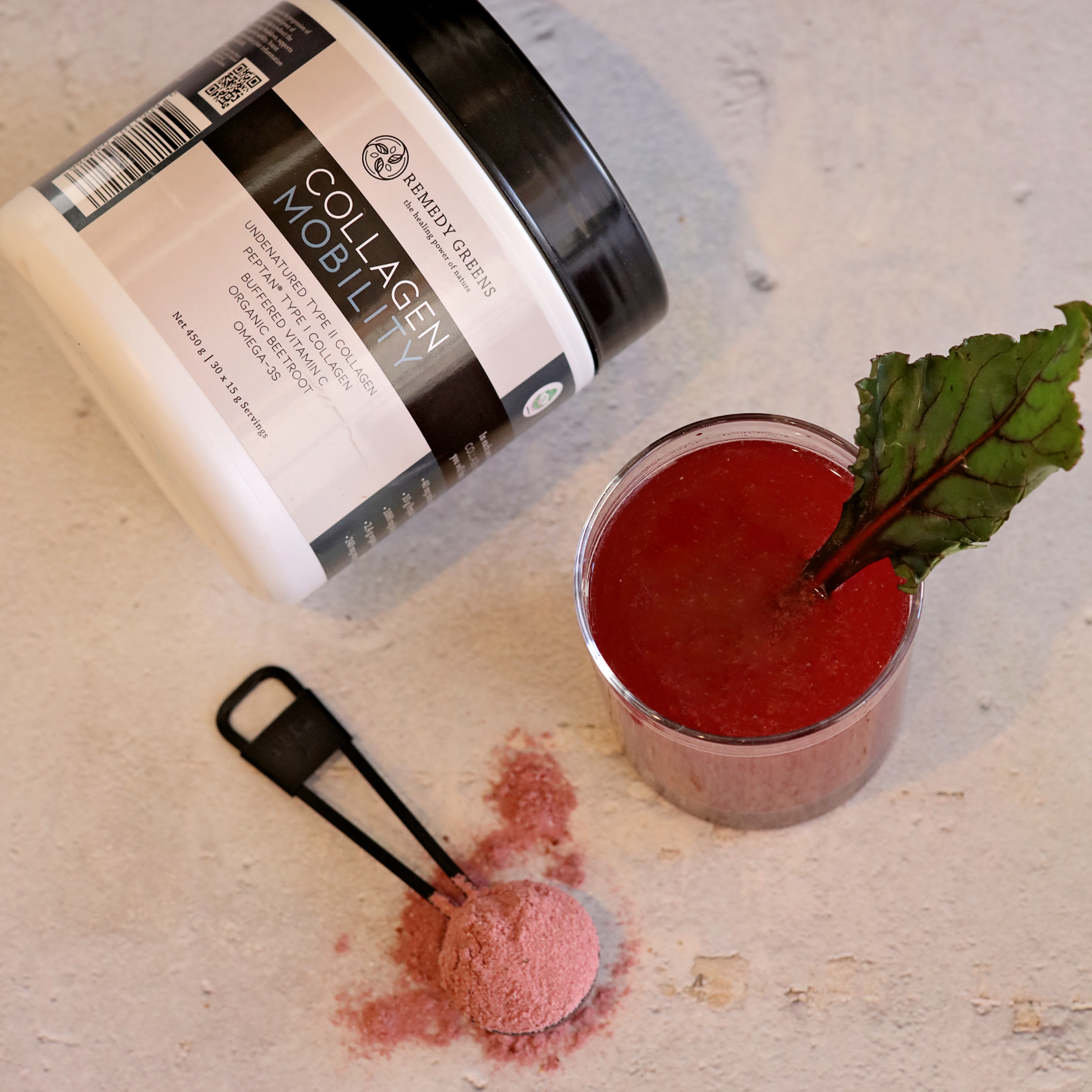Collagen_Mobility_Product_Mixed_In_Water_With_A_Scoop_Of_Red_Powder_On_A_Counter
