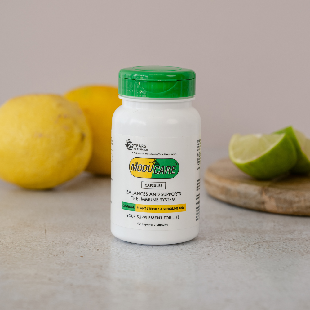 Supplement bottle labeled 'Moducare' with lemons and a lime on a neutral background