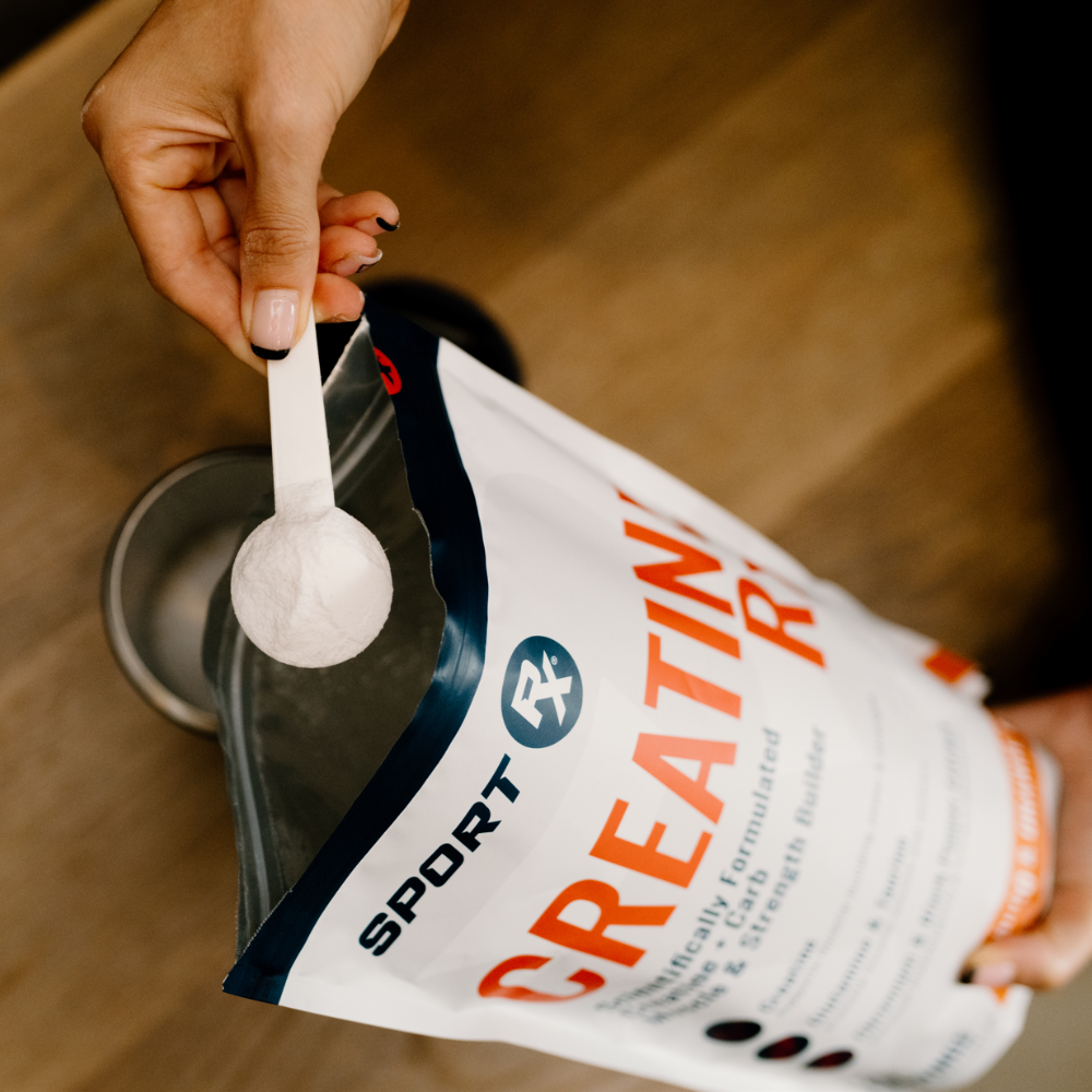 Person measuring Sport Rx creatine powder with a scoop from a labeled bag.
