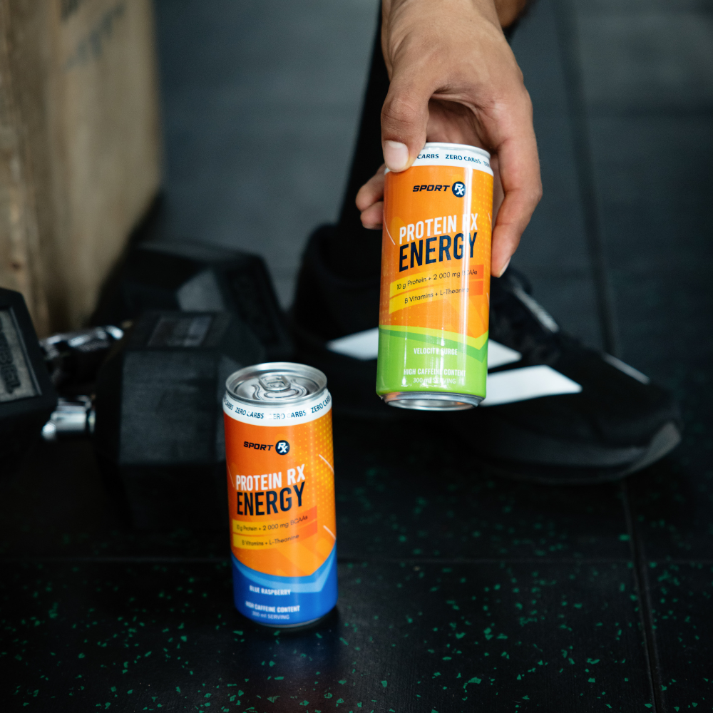 Two cans of Sport Rx Protein RX Energy drink held by a hand on a dark surface