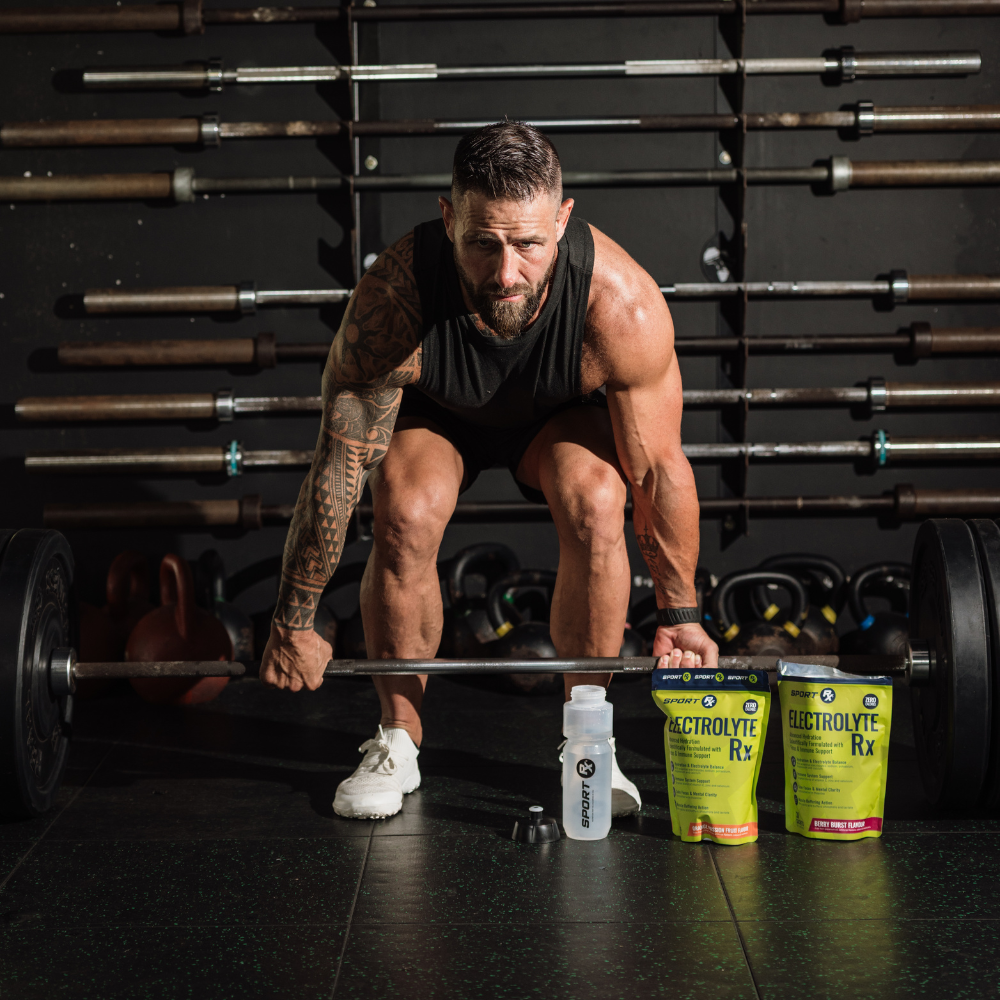Muscular man preparing to lift a barbell with Electrolyte Rx products on the floor in front of him.