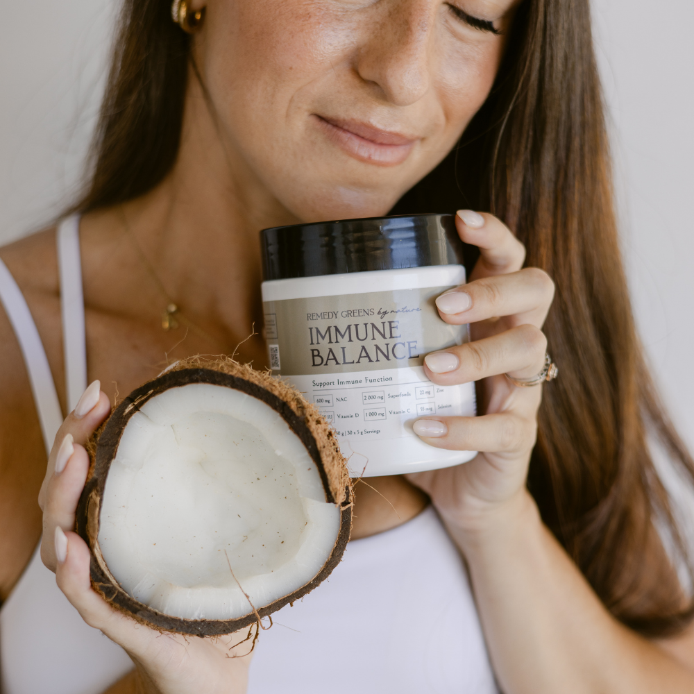 Woman holding a jar labeled 'Immune Balance' by Remedy Greens