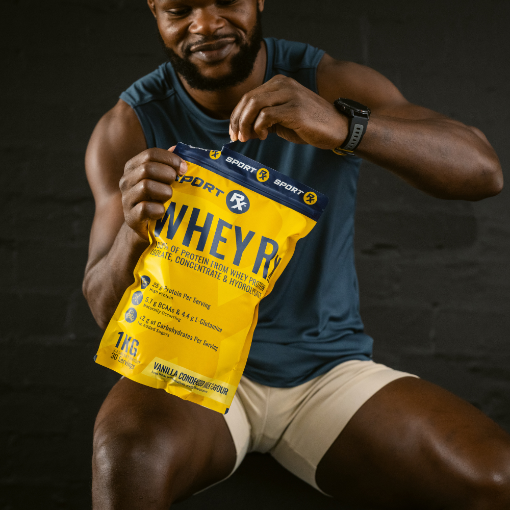 Man holding a Sport Rx Whey protein powder package against a dark background
